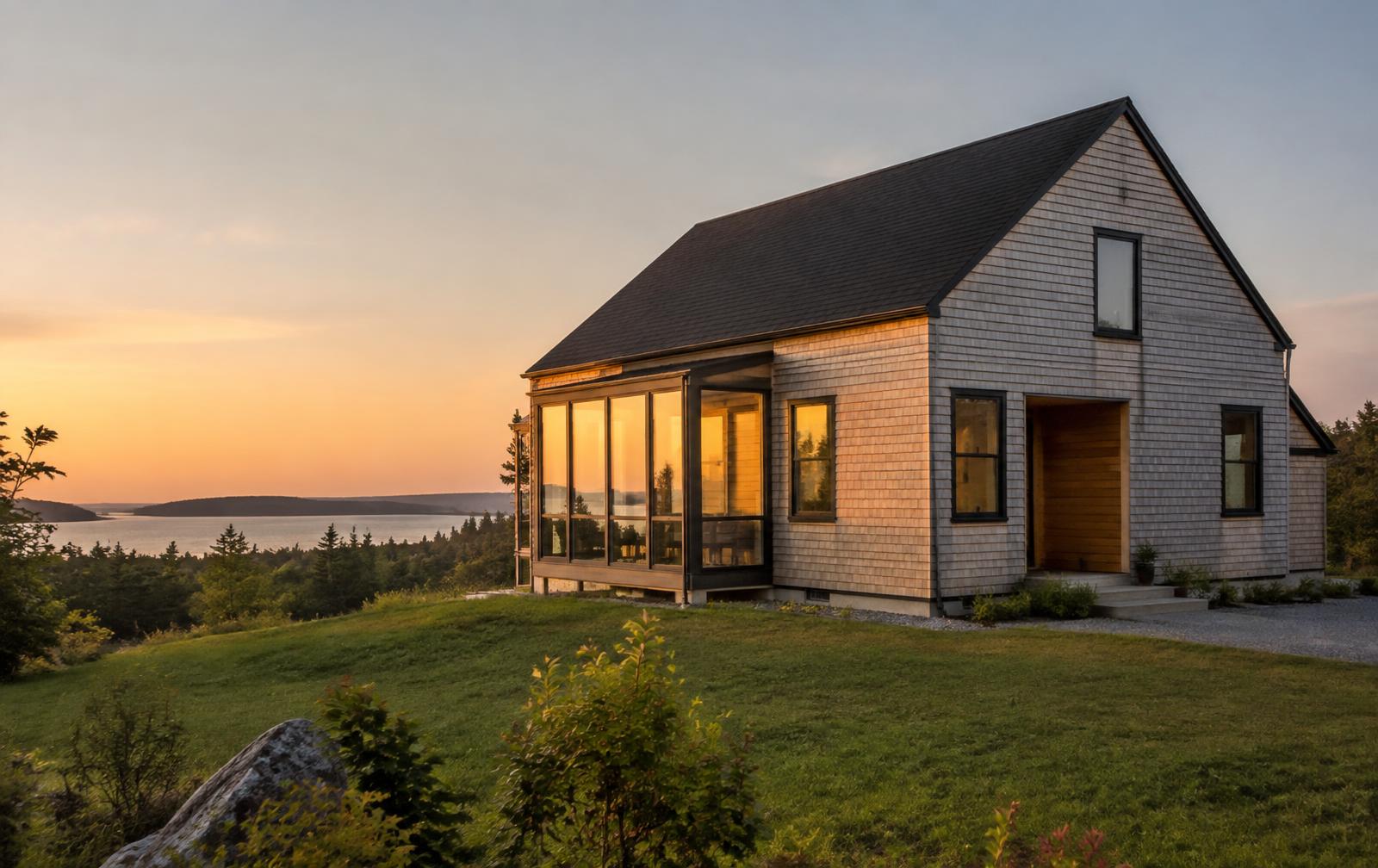 Newly built cedar-shingle home at sunset overlooking the water in Nova Scotia